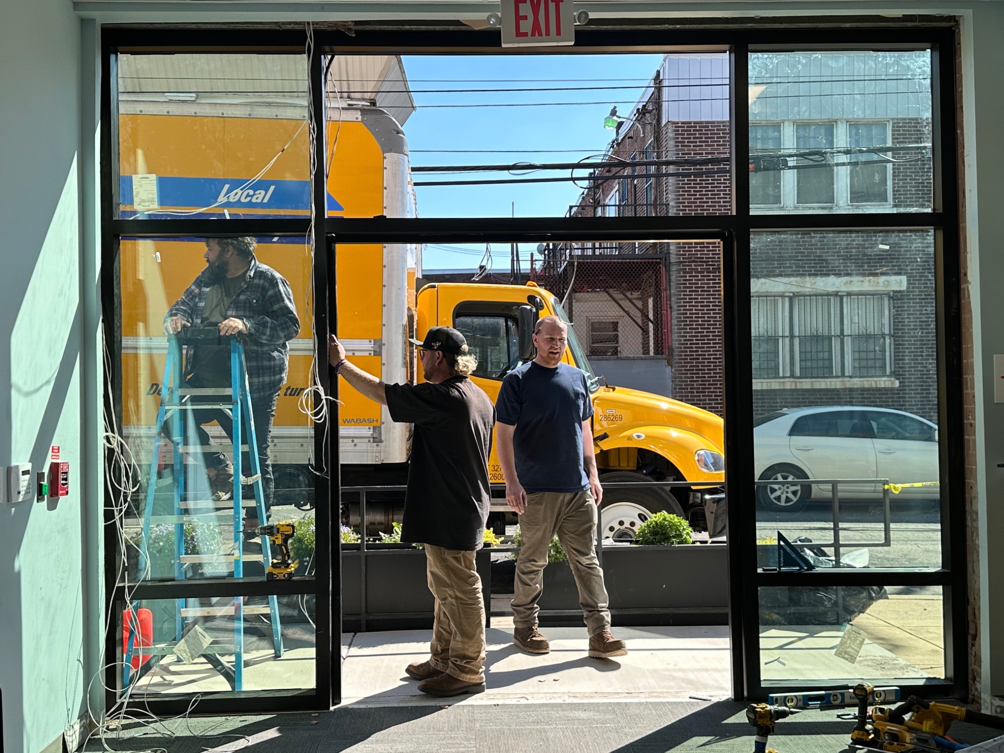 Glazing installers coordinating work at the storefront opening